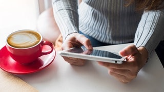 Personen mit iPad am Tisch. Symbolbild für Gerichtsurteile: Was darf ich auf einer Weihnachtsfeier tun und was nicht. 