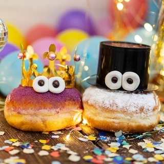 Zwei Berliner mit Augen auf einem Tisch mit Luftschlangen. Symbolbild für Traditionen an Silvester, kuriose Bräuche aus anderen Ländern zu Neujahr.