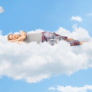 Junge Frau liegt auf Wolken und schläft. Symbolbild für den Selbsttest optimale Schlafdauer: Sind 6 Stunden Schlaf genug?