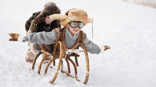 Kinder fahren auf dem Schlitten und genießen das gute Bergwetter