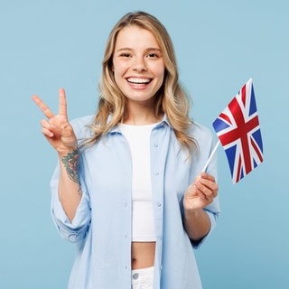 Junge Frau mit England-Flagge in der Hand. Symbolbild für 50 deutsche Redewendungen, wörtlich übersetzt auf Englisch.