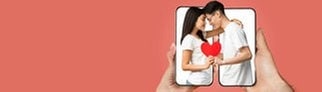 Ein Paar, das sich über zwei Smartphones hinweg mit Herz in der Hand umarmt. Symbolbild für lustige und kitschige Whatsapp-Sprüche und Grüße zum Valentinstag.