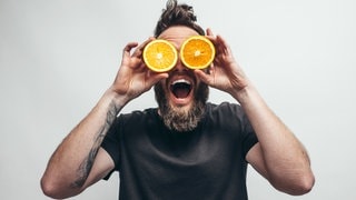 Ein Mann hält sich jeweils eine Orangenhälfte vor die Augen | Vitamin C & Zink bei Erkältung