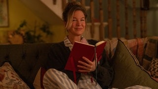 Bridget Jones 4: Die Hauptfigur wird im neuen Kinofilm „Bridget Jones – Verrückt nach ihm“ von Schauspielerin Renée Zellweger gespielt und sitzt mit einem Tagebuch auf der Couch.