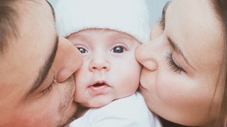 Symbolbild: Glückliche Eltern Küssen ihr Baby.