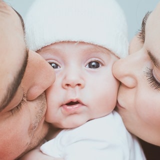 Symbolbild: Glückliche Eltern Küssen ihr Baby.