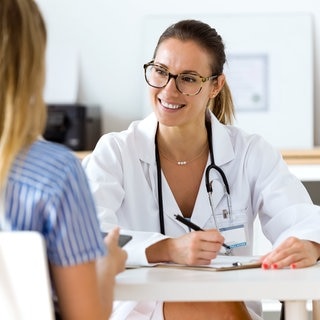 Ärztin in einem Gespräch mit einer Patientin in der Arztpraxis. Symbolbild für typische Sprüche vom Arzt, die wir nicht hören wollen.