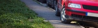 Rotes Auto parkt auf dem Gehweg. | Symbolbild für auf dem Gehweg parken: Ab wann gibts Bußgeld und sogar Punkte?