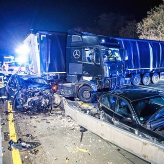 Ein Lkw, der Unfälle auf der A1 und A46 in NRW verursacht hat, steht quer auf der Fahrbahn, daneben zwei stark beschädigte Autos