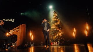 Mark Forster singt auf der Bühne im Theater Baden-Baden neben Weihnachtsbaum im Scheinwerferlicht