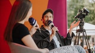 Beim SWR Sommerfestival nehmen Sally Özcan und Max Giesinger eine Folge des Podcasts 1 plus 1 – Freundschaft auf Zeit auf.