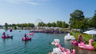 Festivalbesucher sind mit einem großen aufblasbaren Flamingo auf dem Tunisee beim Sea You Festival.