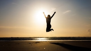 Eine junge Frau springt Strand der Ostfriesischen Insel Langeoog