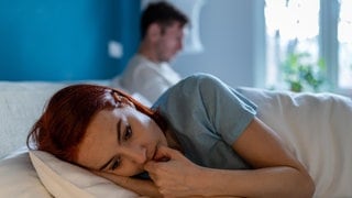 Upset wife lies with her back to husband