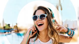 Junge Frau am Strand mit Sonnenbrille und Kopfhörern