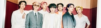 Die siebenköpfige K-Pop-Band BTS trägt weiße und schwarze Anzüge.