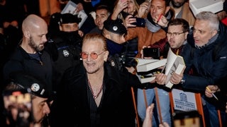 Bono, der Sänger von U2, umringt von Fans und Sicherheitsleuten.