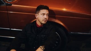 Der Sänger Nico Santos sitzt vo einem Auto