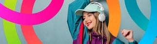 Eine Frau trägt ein Outfit wie aus den 90er-Jahren und tanzt zur Musik, die sie über Kopfhörer hört