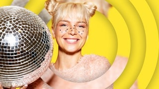 Eine blonde junge Frau mit kleinen Sternen im Gesicht hält eine Disokugel in der Hand. (Foto: Adobe Stock, deniskomarov) Eine blonde junge Frau mit kleinen Sternen im Gesicht hält eine Disokugel in der Hand.