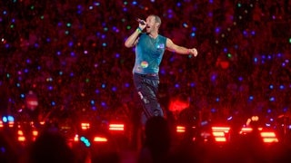 Chris Martin, Sänger der britischen Band Coldplay steht bei einem Konzert im Rahmen der „Music of the Spheres Tour 2024“ bei strömendem Regen in der Merkur auf der Bühne.