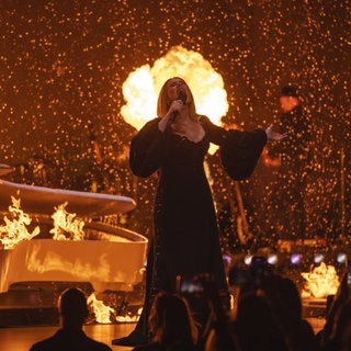 Adele singt bei ihrem vorerst letzten Konzert. Im Hintergrund sind Flammen zu sehen.