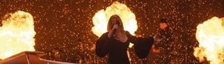 Adele singt bei ihrem vorerst letzten Konzert. Im Hintergrund sind Flammen zu sehen.