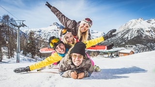 Eine Gruppe von Freunden liegt aufeinander und feiert beim Après-Ski den Hit „Wackelkontakt“ von Oimara 