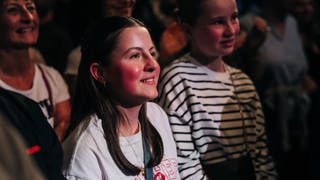 Fan Amelie übergibt Asdis ein Freundschaftsarmbändchen beim New Pop Festival.