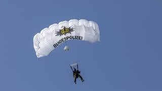 Polizist der Spezialeinheit GSG9 mit weissem Fallschirm, auf dem Bundespolizei steht.