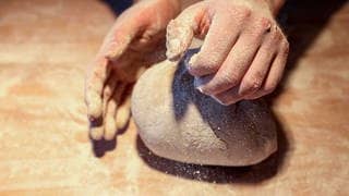 Ein Bäcker formt mit seinen Händen ein Brot