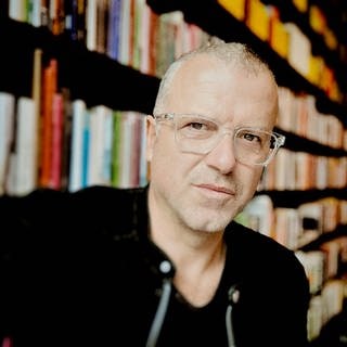 Portrait Bernhard Aichner vor Bücherregal