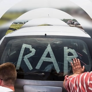 Rock am Ring: Zwei Menschen schieben ein Auto mit dem Schriftzug „RaR“.