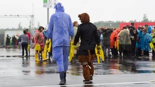 Zwei Festivalbesucher laufen über nassen Asphalt über das Gelände von Rock am Ring.