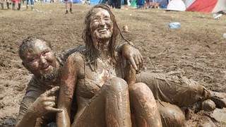 Ein Mann und eine Frau wälzen sich beim Musikfestival Rock am Ring im Schlamm.