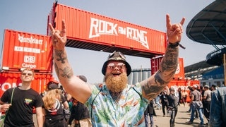 Ein junger Mann mit Bart und Hawai-Hemd steht vor dem Eingang zu Rock am Ring