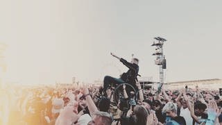 Ein junger Mann macht im Rollstuhl sitzend Crowdsurfing beim Auftritt von Papa Roach bei Rock am Ring 2023