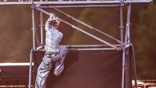 Der amerikanische Rapper Machine Gun Kelly klettert bei Rock am Ring den Mast hoch