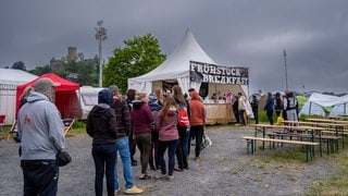 Eine Schlange Menschen steht vor einem Zelt bei Rock am Ring, bei dem es etwas zum Frühstück gibt