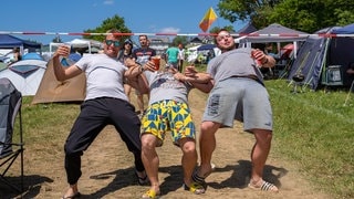 3 Männer beim Limbo unter einem Absperrband