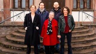 Cast vom Tatort "Lenas Tante" vor dem Drehstart auf einer Treppe vor einem Haus. 