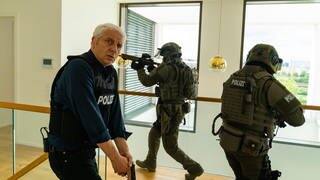Tatort München „Game Over“: Kommissar Franz Leitmayr bewaffnet in einem treppenhaus mit einem SEK. Unsere Kritikerin findet den neuen Tatort richtig gut!