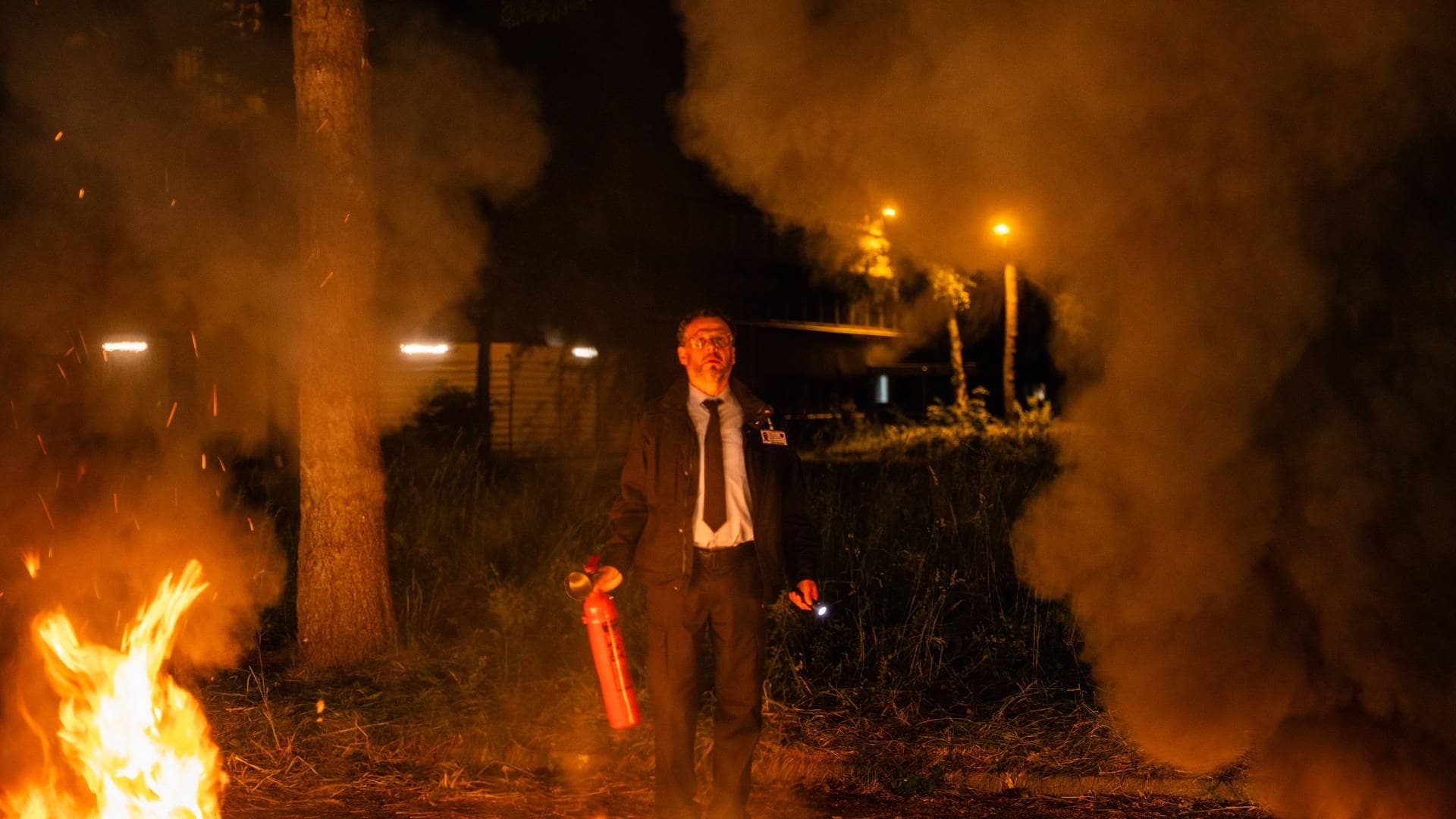 Polizeiruf „Funkensommer“ München: Ein Mann steht mit einem Feuerlöscher vor hohen Flammen