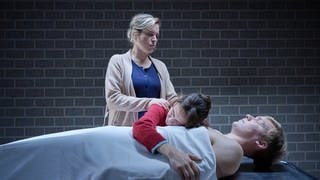 Ausschnitt aus dem Tatort Franken „Trotzdem“: Die Schwestern Maria (Mercedes Müller, rechts) und Lisa (Anne Haug, links) bei der Leiche ihres Bruders Lenni (Neil Körger), der sich aus Verzweiflung das Leben genommen hat.