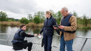 Polizeiruf „Wasserwege“ am 13.10.24: Die Kriminalkommissare Vincent Ross (André Kaczmarczyk, li.) und Karl Rogov (Frank Leo Schröder, re.) suchen, mit Unterstützung der Kollegin von der Wasserschutzpolizei Gunde Johannsen (Petra Van de Voort, mi.), nach dem Tatort, der sich in der Nähe des Schiffshebewerks Niederfinow am Oder-Havel-Kanal befinden muss.