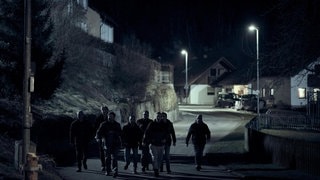 Szenenbild aus dem Tatort aus Stuttgart am 17.11. Eine Gruppe von Menschen läuft nachts bei Dunkelheit durchs Dorf.