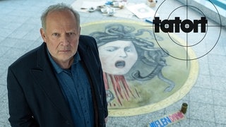 Tatort Kiel „Borowski und das Haupt der Medusa“: Kommissar Borowski vor einem gemalten Medusa Kopf. Er kann den neuen Fall nicht ruhen lassen. 